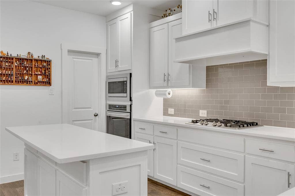 525 Division Street, Plano, TX 75075 White cabinetry, light-toned subway tile backsplash, white countertops, built-in microwave, and a gas cooktop