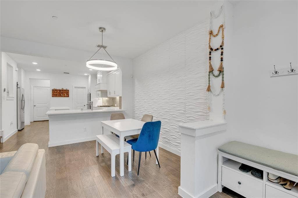 525 Division Street, Plano, TX 75075 Open-concept living space featuring wood-finish flooring, a contemporary circular pendant light, and a textured accent wall