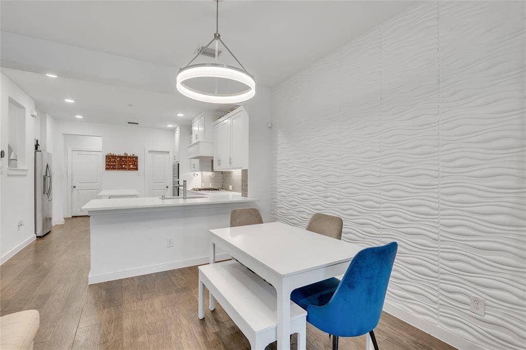 525 Division Street, Plano, TX 75075 Open-concept dining area with wood-finish flooring, a contemporary circular pendant light, and a textured accent wall