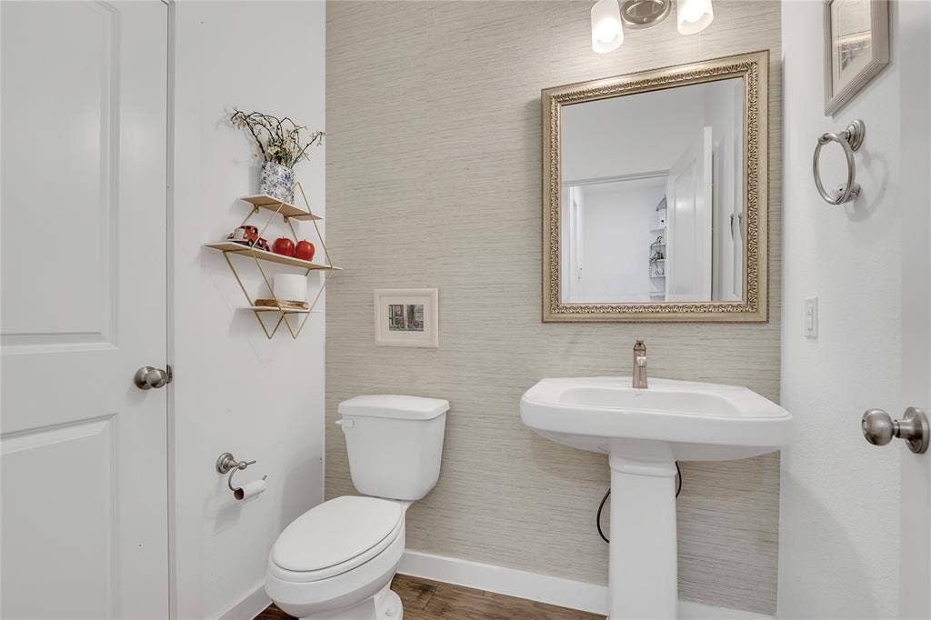525 Division Street, Plano, TX 75075 Pedestal sink, brushed nickel faucet, framed mirror, wall-mounted light fixture, and wood-finish flooring