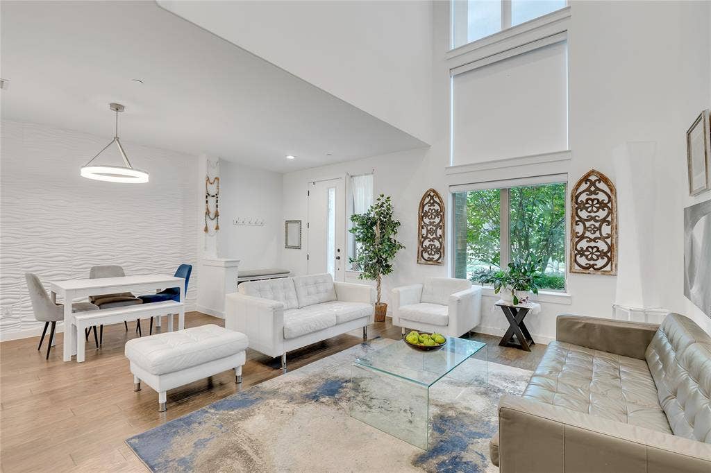 525 Division Street, Plano, TX 75075 Expansive living area with high ceilings, large windows, wood-finish flooring, a contemporary chandelier, and a textured accent wall
