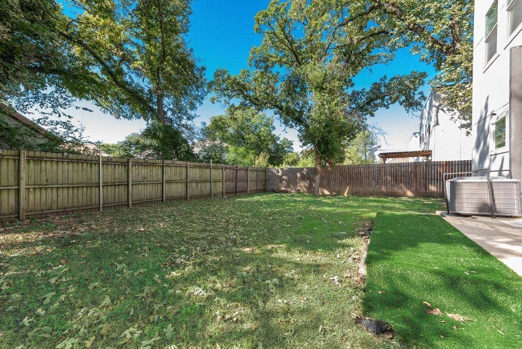 Expansive backyard featuring a partial artificial turf section, natural grass, and a wood privacy fence