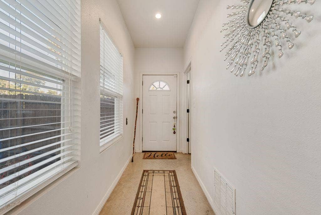 Recessed lighting illuminates the entry hall featuring a solid entry door with a decorative arch window