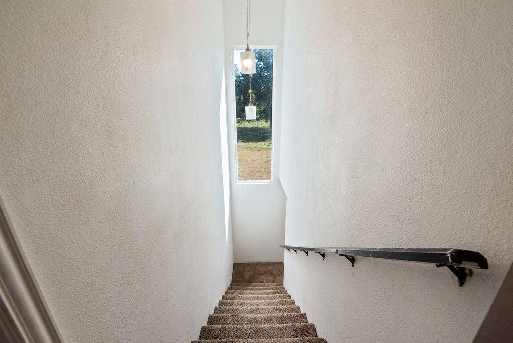 Stairwell with a window, textured wall finish, and a dark-toned handrail