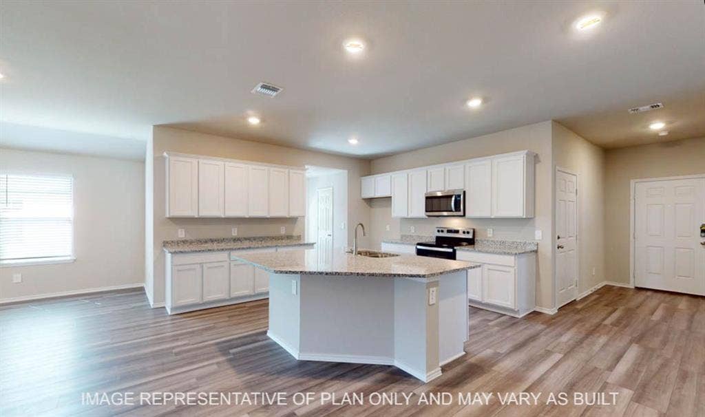 10220 Altair Drive, Waco, TX 76708 Open-concept kitchen with a central island, stainless steel appliances, granite countertops, white cabinetry, and wood-finish flooring