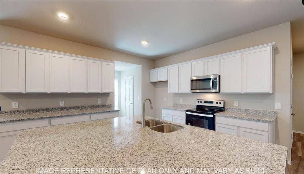 10220 Altair Drive, Waco, TX 76708 Kitchen featuring extensive light-toned cabinetry, speckled countertops, stainless steel microwave, and a double basin sink with a high-arc faucet