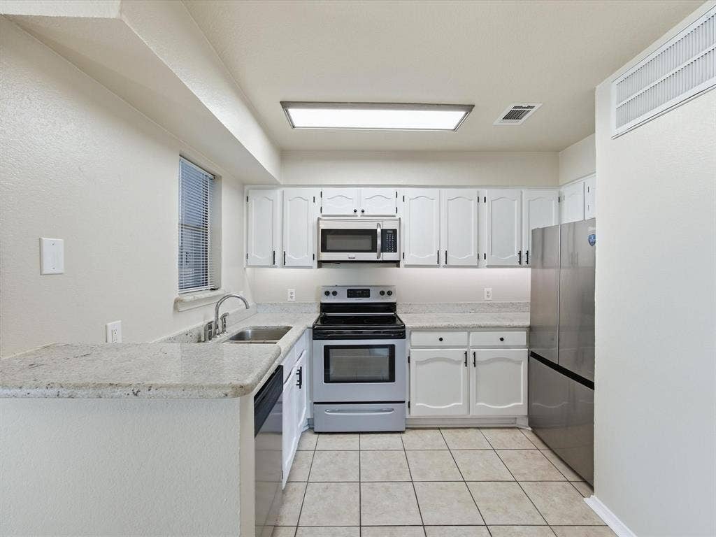 3129 Sondra Drive, #206, Fort Worth, TX 76107 Kitchen featuring white cabinetry, stainless steel appliances, a stainless steel sink, and light-toned countertops
