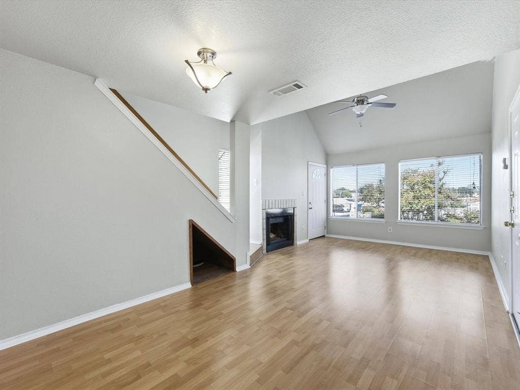 3129 Sondra Drive, #206, Fort Worth, TX 76107 Vaulted ceiling, wood-finish flooring, multiple windows with blinds, built-in fireplace, and a ceiling fan