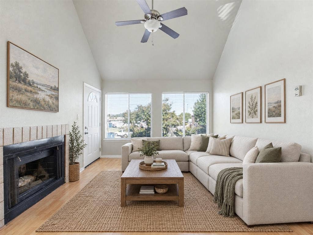 3129 Sondra Drive, #206, Fort Worth, TX 76107 Vaulted ceiling with ceiling fan, wood-finish flooring, fireplace with brick surround, multiple windows, and a panel door with an arched glass insert