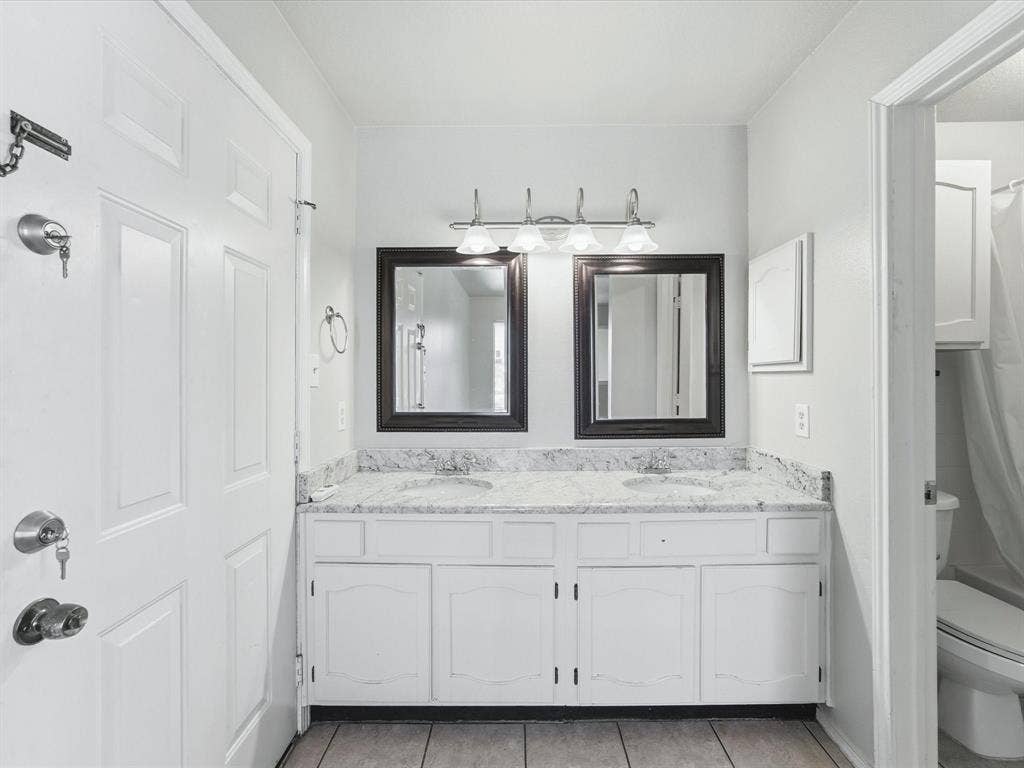 3129 Sondra Drive, #206, Fort Worth, TX 76107 Double vanity with undermount sinks, stone countertops, framed mirrors, and chrome light fixture