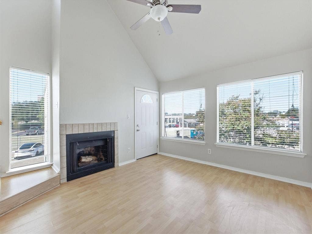 3129 Sondra Drive, #206, Fort Worth, TX 76107 Vaulted ceiling, wood-finish flooring, fireplace with brick surround, multiple windows with blinds, and a ceiling fan