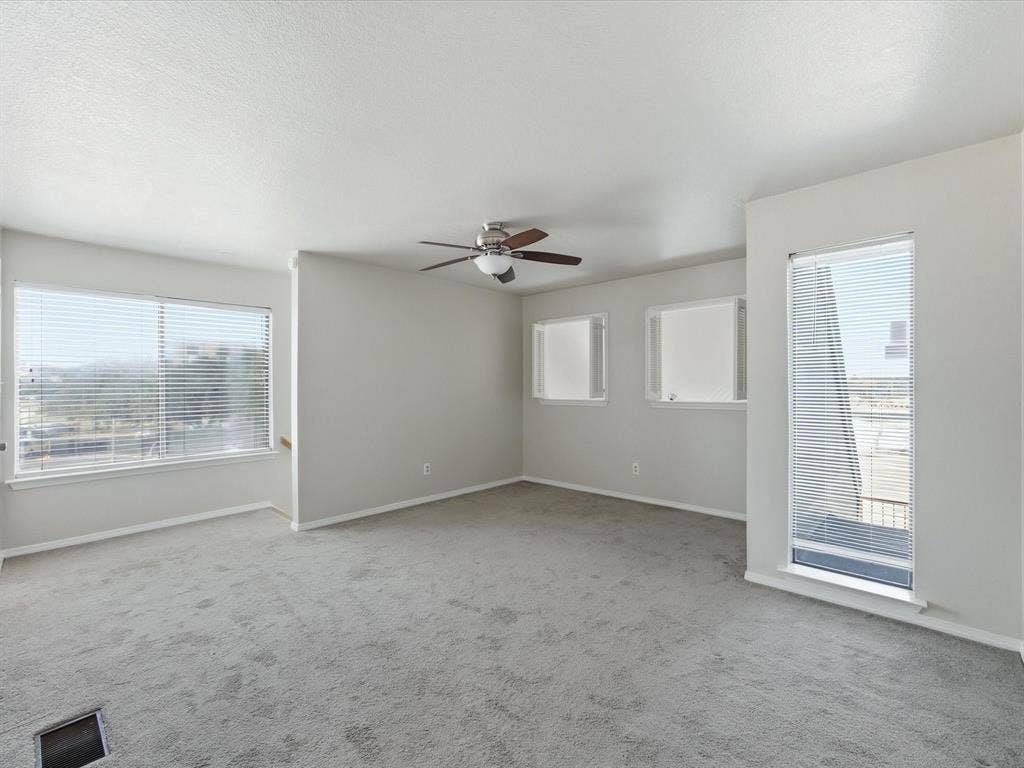 3129 Sondra Drive, #206, Fort Worth, TX 76107 Spacious room featuring light gray carpeting, multiple windows with blinds, a ceiling fan, and white trim