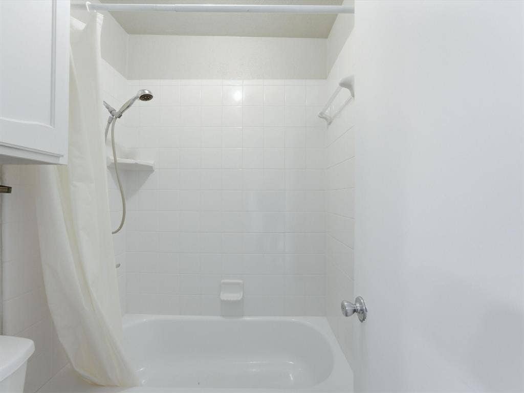 3129 Sondra Drive, #206, Fort Worth, TX 76107 Bathtub with white tile surround, integrated showerhead, and wall-mounted soap dish