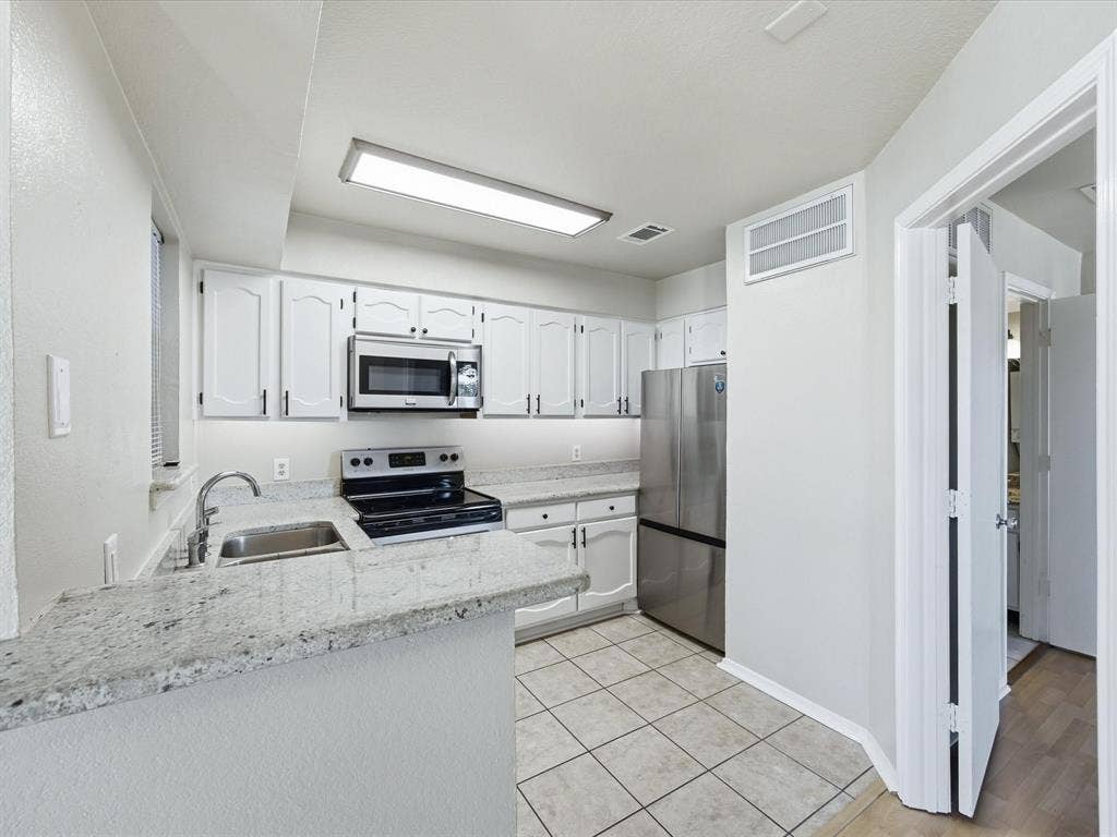 3129 Sondra Drive, #206, Fort Worth, TX 76107 White cabinetry, stainless steel appliances, tile flooring, light-toned countertops, and recessed lighting