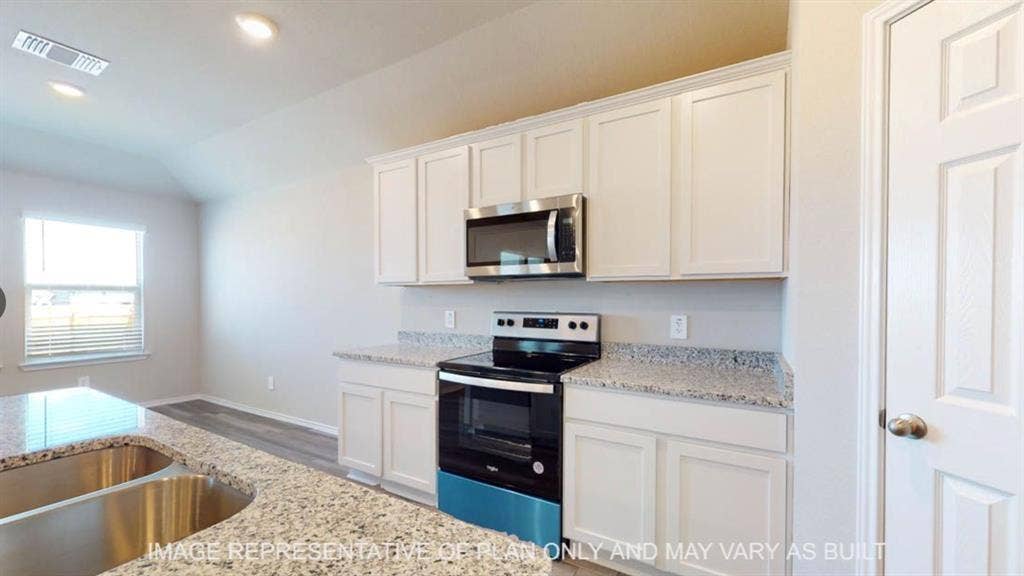10108 Altair Drive, Waco, TX 76708 White shaker cabinetry with stainless steel appliances, speckled countertops, and a double basin sink