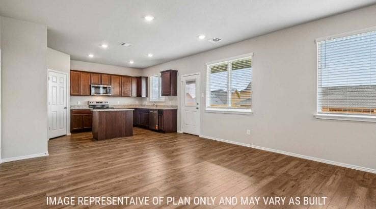 10101 Altair Drive, Waco, TX 76708 Wood-finish flooring throughout, recessed lighting, and a kitchen featuring dark wood cabinetry, a center island, and stainless steel appliances