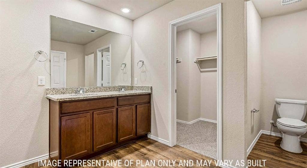 10101 Altair Drive, Waco, TX 76708 Double vanity with a speckled countertop, undermount sinks, and wood-finish cabinetry
