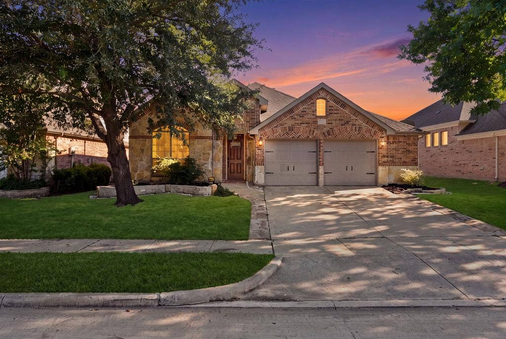 242 Cox Drive, Fate, TX 75087 Brick and stone exterior with arched window, two-car garage, concrete driveway, and manicured landscaping