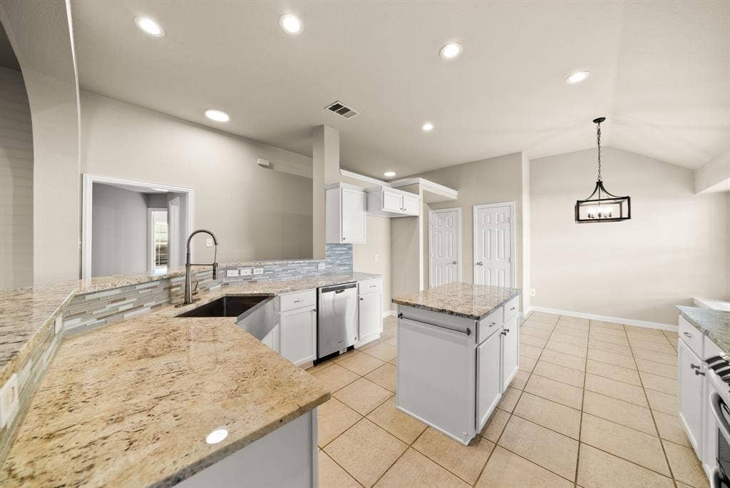 242 Cox Drive, Fate, TX 75087 Spacious kitchen featuring granite countertops, stainless steel appliances, a large center island with prep space, tile flooring, recessed lighting, and a pendant fixture overhead