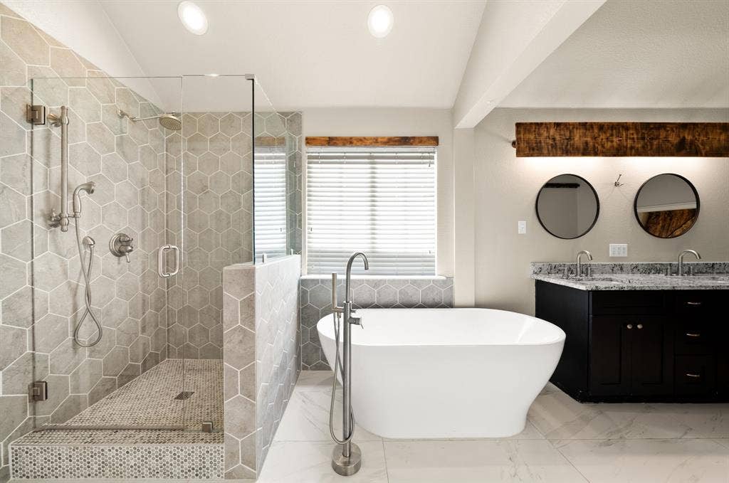 242 Cox Drive, Fate, TX 75087 Freestanding soaking tub, walk-in shower with glass enclosure, dual vanity with undermount sinks, wood-finish beam with integrated lighting, and hexagonal tile accents