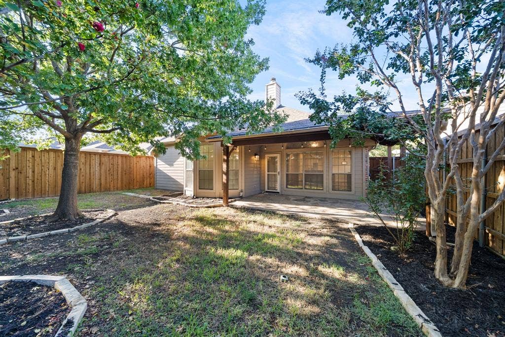 242 Cox Drive, Fate, TX 75087 Expansive backyard featuring a covered patio, privacy fencing, mature trees, and landscaping beds