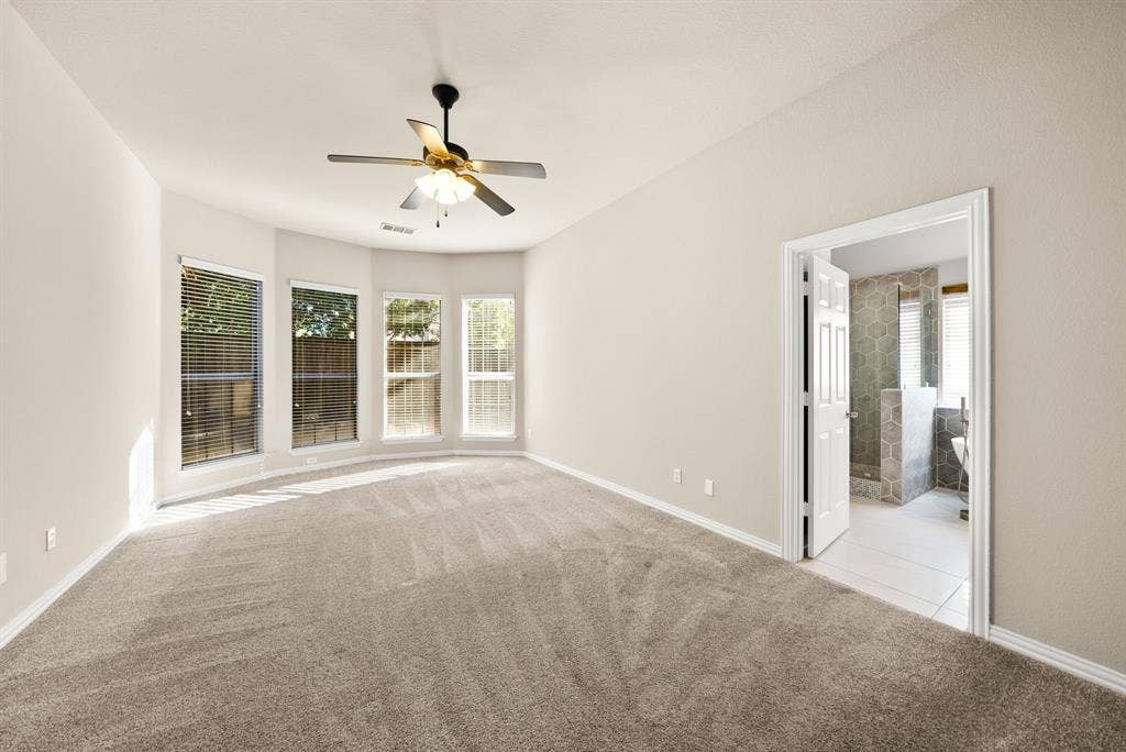 242 Cox Drive, Fate, TX 75087 Spacious room featuring neutral carpeting, a ceiling fan, and a bay window configuration with multiple windows
