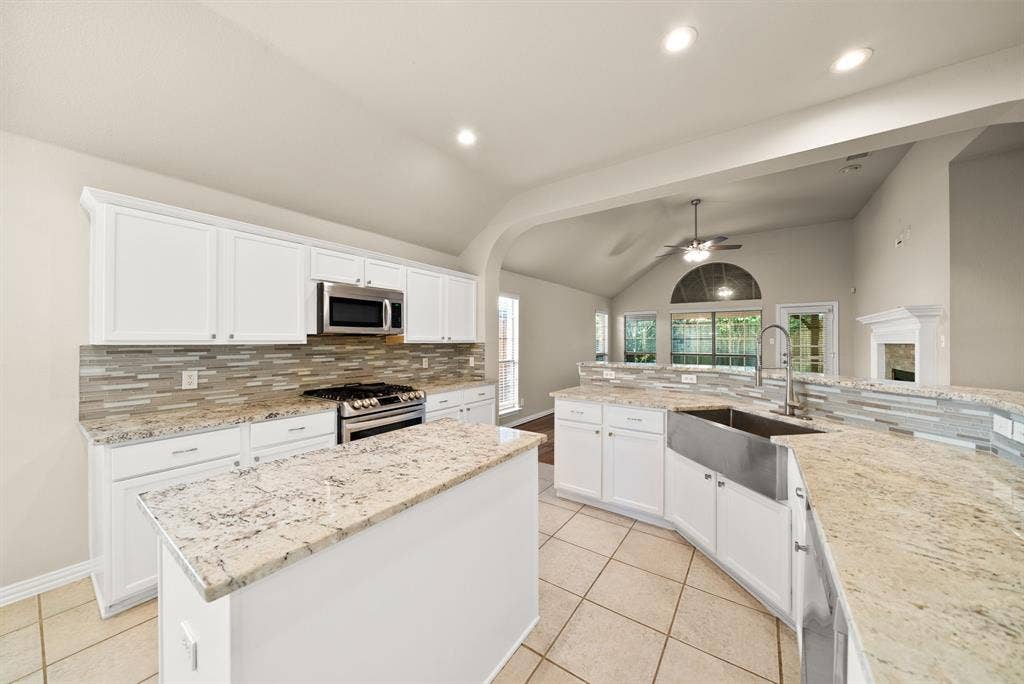 242 Cox Drive, Fate, TX 75087 Kitchen featuring white cabinetry, light-toned countertops, a stainless steel farmhouse sink, and a tiled backsplash