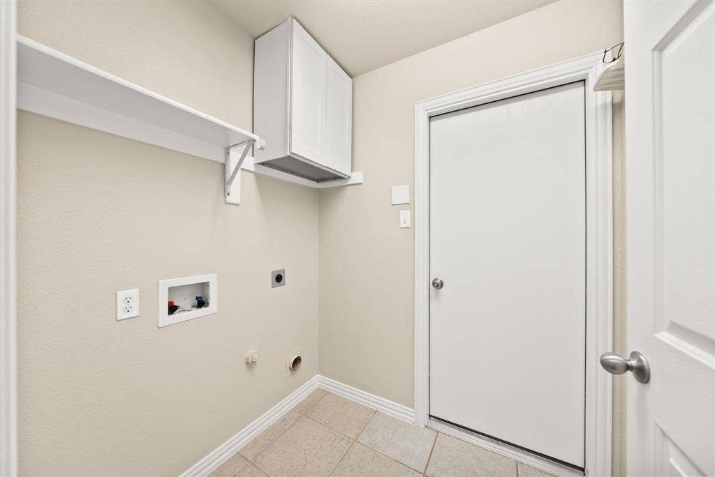 242 Cox Drive, Fate, TX 75087 Laundry area with tiled flooring, wall-mounted shelving, and upper cabinetry