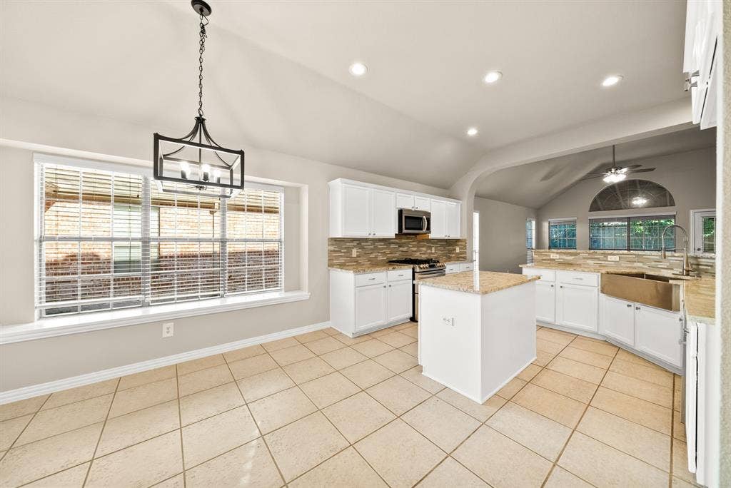242 Cox Drive, Fate, TX 75087 Kitchen featuring white cabinetry, a central island with a granite countertop, stainless steel appliances, a tile backsplash, and recessed lighting