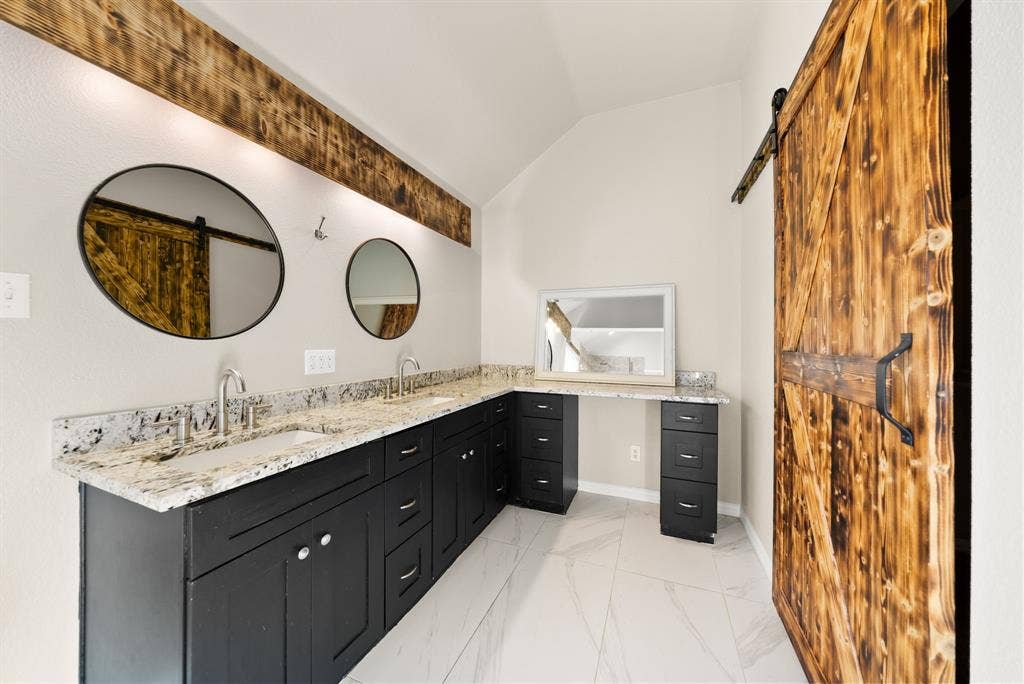 242 Cox Drive, Fate, TX 75087 Dual vanity with granite countertops, undermount sinks, and dark wood cabinetry