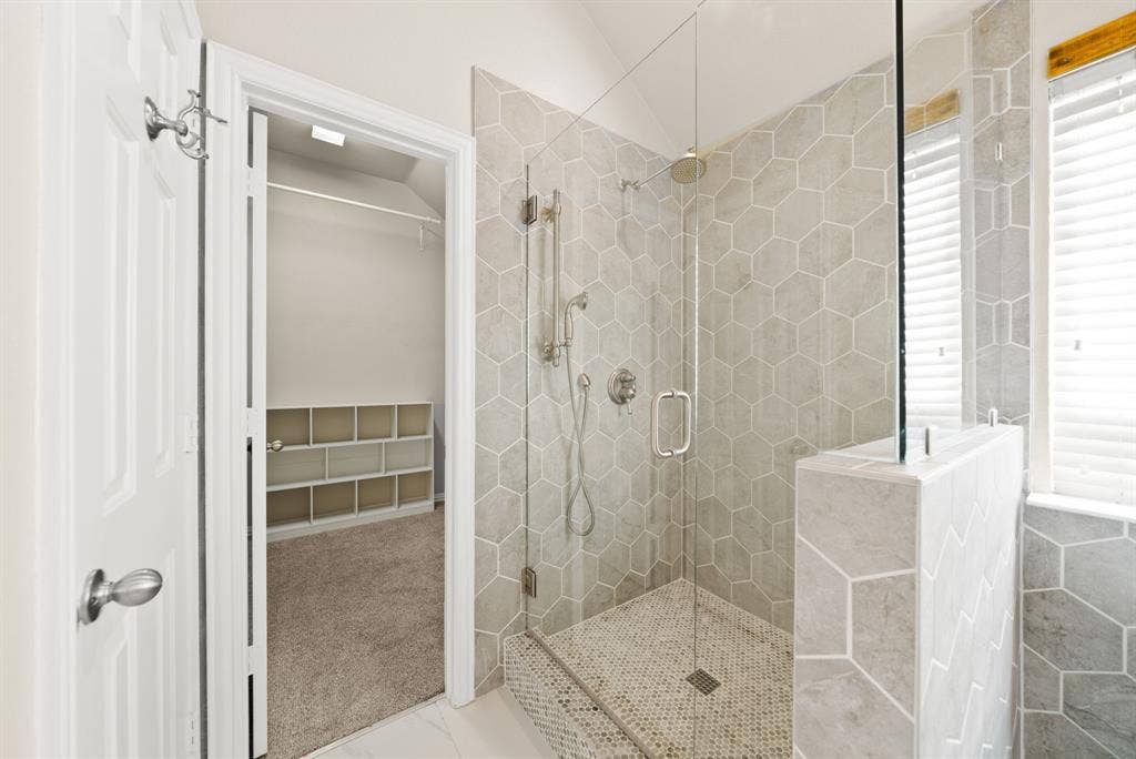 242 Cox Drive, Fate, TX 75087 Walk-in shower with hexagonal tile surround, glass enclosure, and mosaic floor