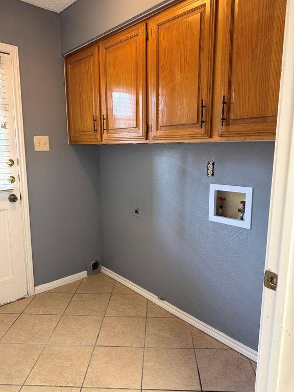 2200 W Park Boulevard, #1003, Plano, TX 75075 Utility area featuring wood cabinetry with black hardware, tile flooring, and dedicated laundry hookups