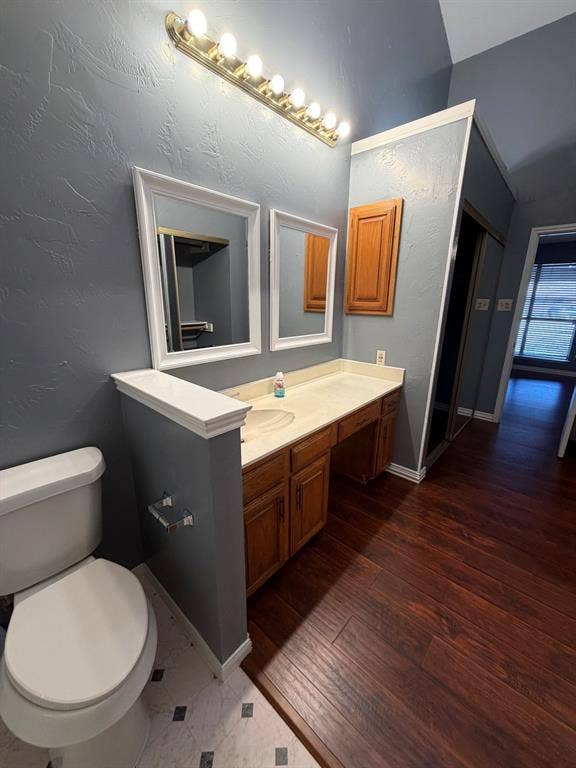 2200 W Park Boulevard, #1003, Plano, TX 75075 Bathroom vanity featuring wood-finish cabinetry, a solid surface countertop, an integrated sink, dual wall-mounted mirrors, and an eight-bulb overhead fixture