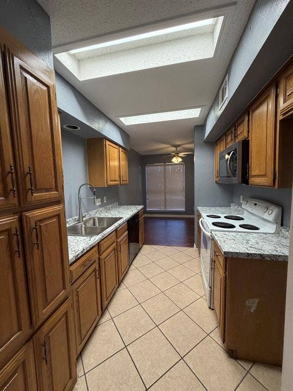 2200 W Park Boulevard, #1003, Plano, TX 75075 Kitchen featuring natural wood cabinetry, stone-patterned countertops, dual skylights, tile flooring, and stainless steel integrated appliances