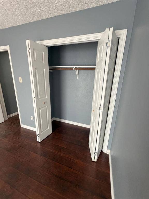2200 W Park Boulevard, #1003, Plano, TX 75075 Closet featuring white six-panel bifold doors and a built-in hanging rod, complemented by dark wood-finish flooring