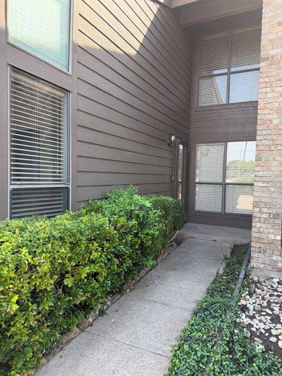 2200 W Park Boulevard, #1003, Plano, TX 75075 Exterior facade featuring horizontal siding and brick masonry, multi-pane windows, and a concrete walkway bordered by manicured shrubs