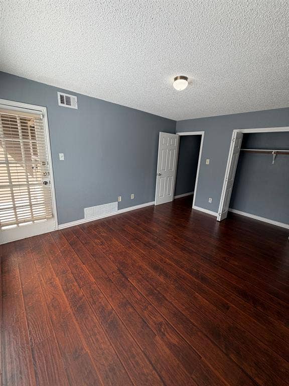 2200 W Park Boulevard, #1003, Plano, TX 75075 Interior space featuring dark-toned wood-finish flooring, neutral-hued walls, a multi-panel door, and a built-in closet with an integrated hanging rod