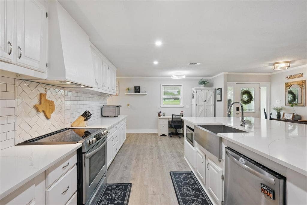 5247 Fm 1569, Farmersville, TX 75442 Spacious kitchen featuring white cabinetry, light-toned countertops, a stainless steel farm sink, and wood-finish flooring