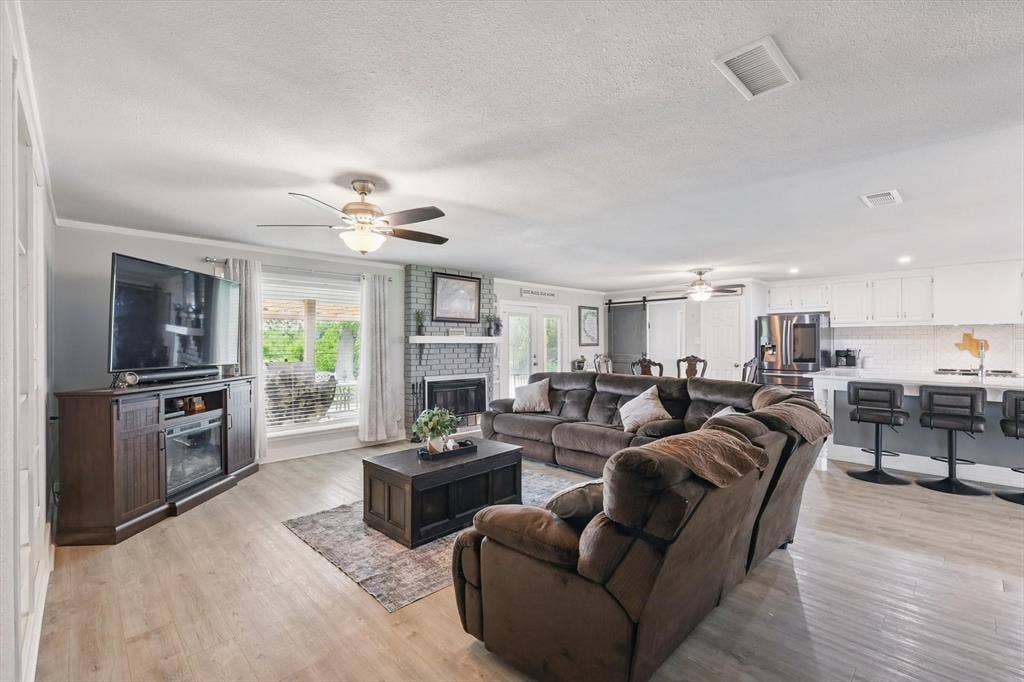 5247 Fm 1569, Farmersville, TX 75442 Open-concept living space featuring wood-finish flooring, a brick-surround fireplace, and a ceiling fan