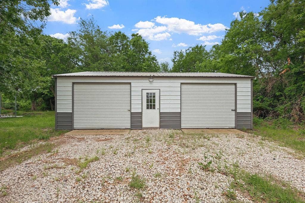 5247 Fm 1569, Farmersville, TX 75442 Metal storage building with two roll-up garage doors, a pedestrian entry door, and a gravel driveway
