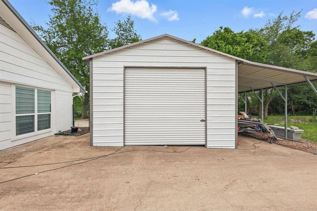 5247 Fm 1569, Farmersville, TX 75442 Metal utility building with a roll-up door, an attached open-sided carport, and a concrete pad