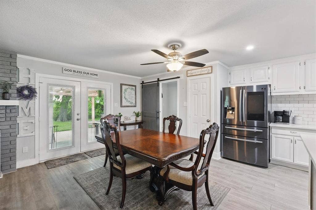 5247 Fm 1569, Farmersville, TX 75442 Open kitchen and dining area featuring stainless steel appliances, white cabinetry, subway tile backsplash, wood-finish flooring, and a ceiling fan with integrated lighting