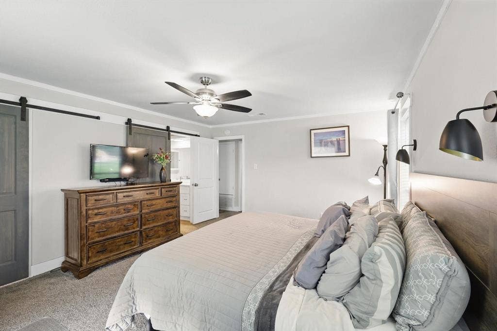 5247 Fm 1569, Farmersville, TX 75442 Ceiling fan with integrated lighting, two barn doors with dark wood finish, wall-mounted sconce lighting, and crown molding