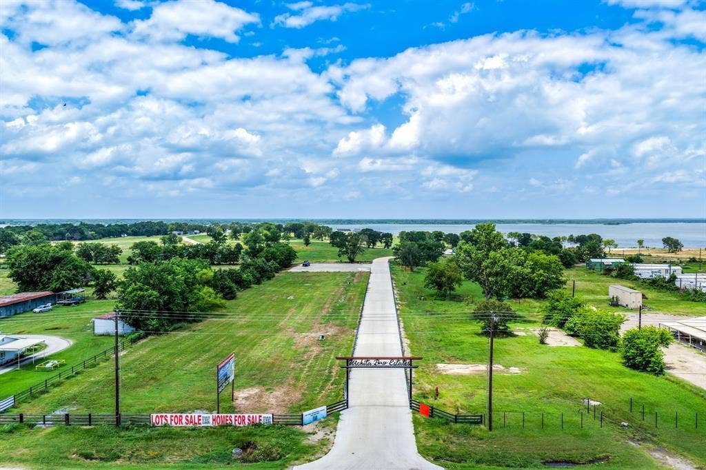 200 Caro Drive, West Tawakoni, TX 75454 Expansive land parcel featuring a paved thoroughfare, gated entry archway, and mature tree clusters