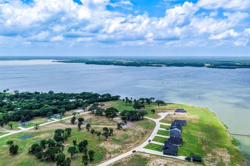 200 Caro Drive, West Tawakoni, TX 75454 Aerial perspective of waterfront land featuring expansive shoreline, mature trees, and paved road access