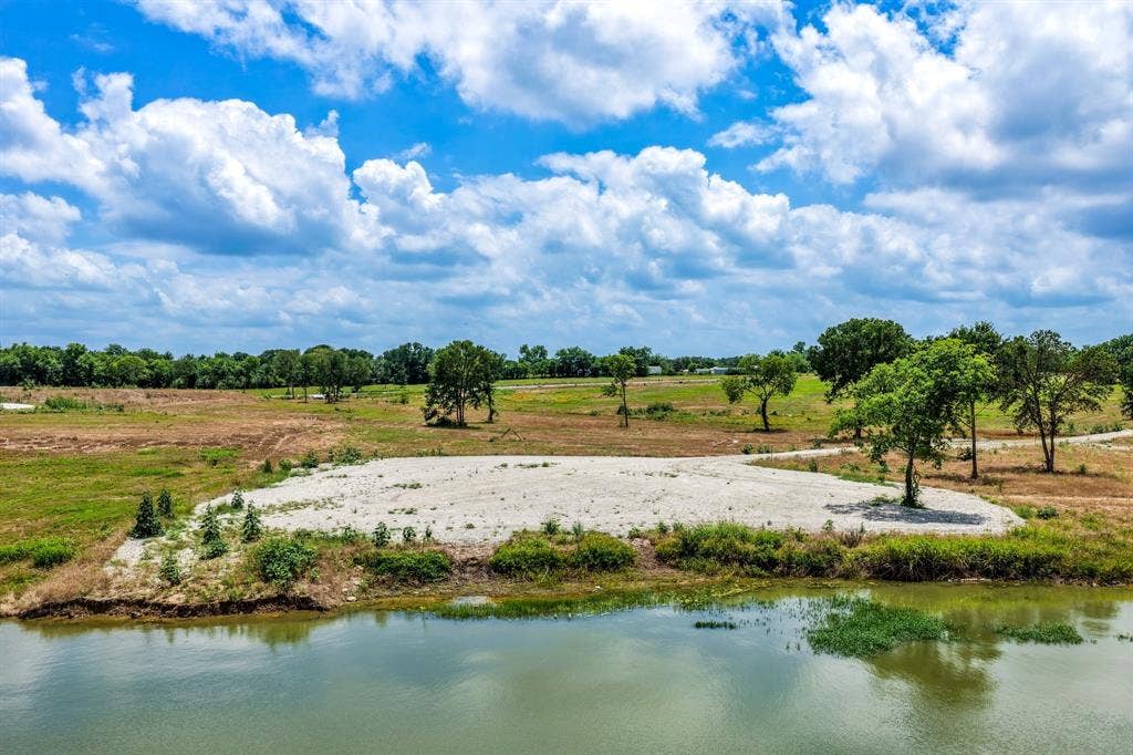 200 Caro Drive, West Tawakoni, TX 75454 Expansive waterfront acreage featuring a leveled gravel base, open grassy terrain, and mature trees