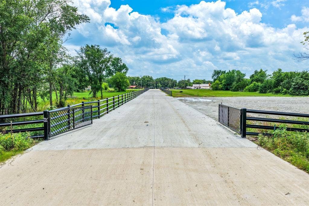 200 Caro Drive, West Tawakoni, TX 75454 Concrete driveway featuring metal fencing, gated entry, and expansive surrounding acreage