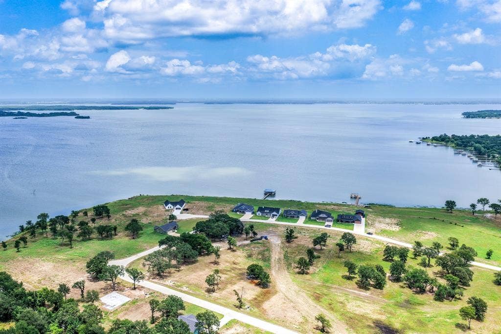 200 Caro Drive, West Tawakoni, TX 75454 Aerial perspective of waterfront acreage featuring expansive shoreline, mature oak trees, paved access roads, and multiple residential structures