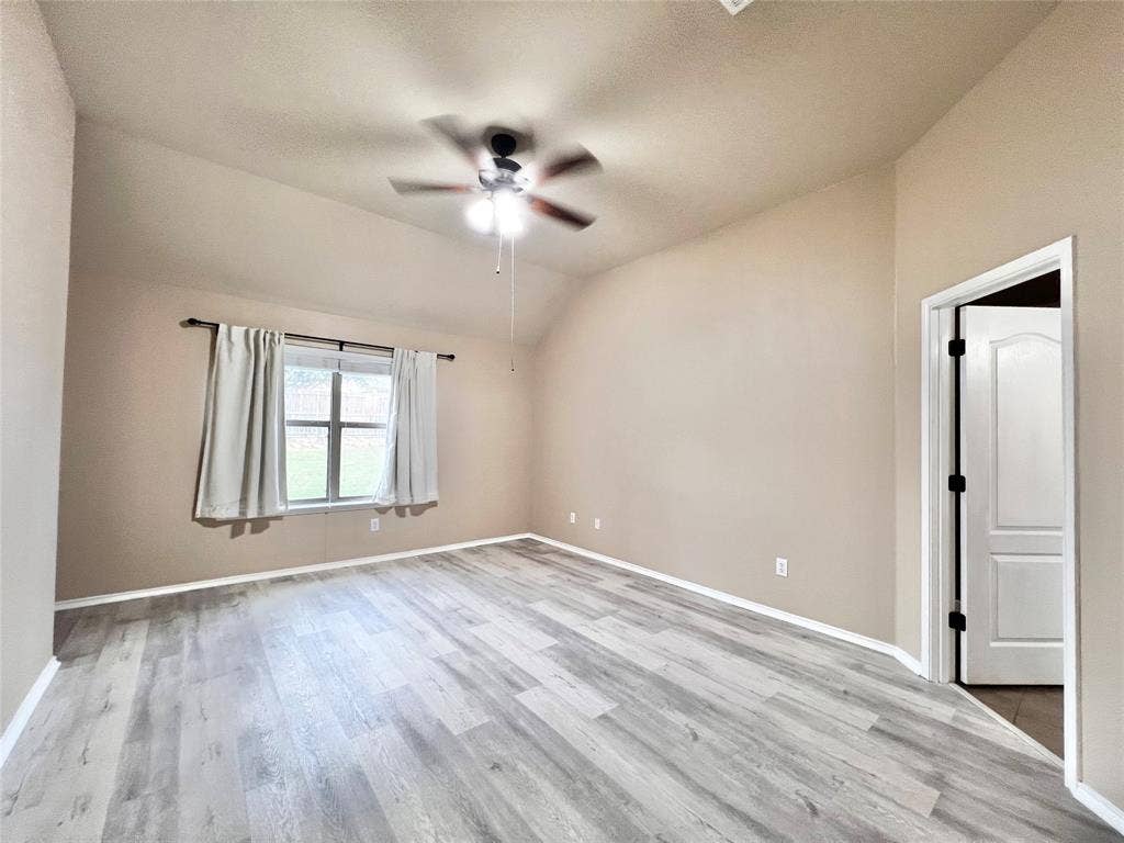 5204 Bear Valley Drive, McKinney, TX 75071 Vaulted ceiling with a ceiling fan, wood-finish flooring, and a multi-pane window