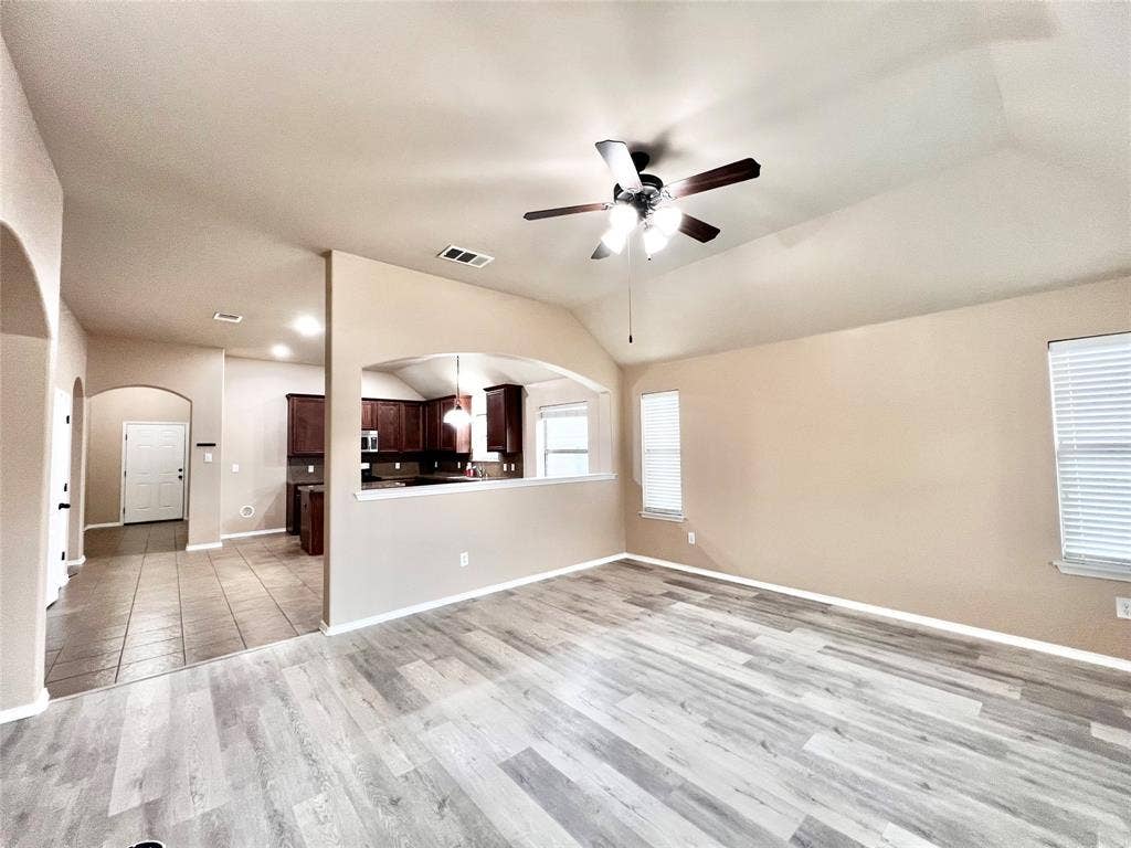 5204 Bear Valley Drive, McKinney, TX 75071 Vaulted ceilings with a ceiling fan, wood-finish flooring, multiple windows with blinds, and an arched entryway